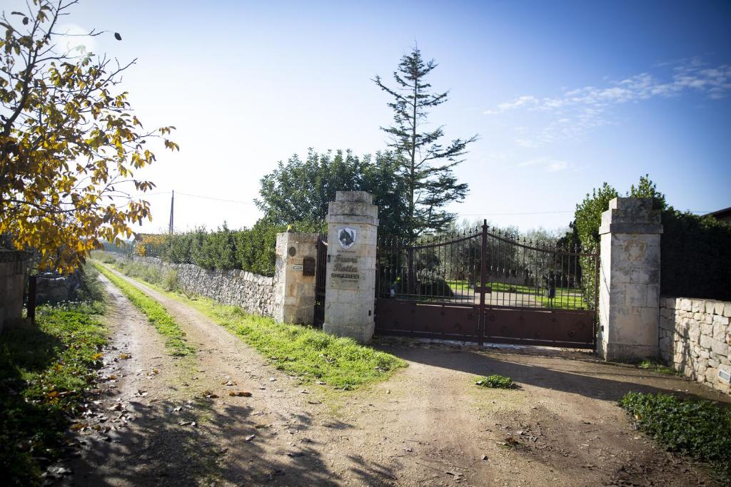 une clôture en pierre avec un portail et un chemin de terre dans l'établissement B&B Masseria SERRI, à Putignano