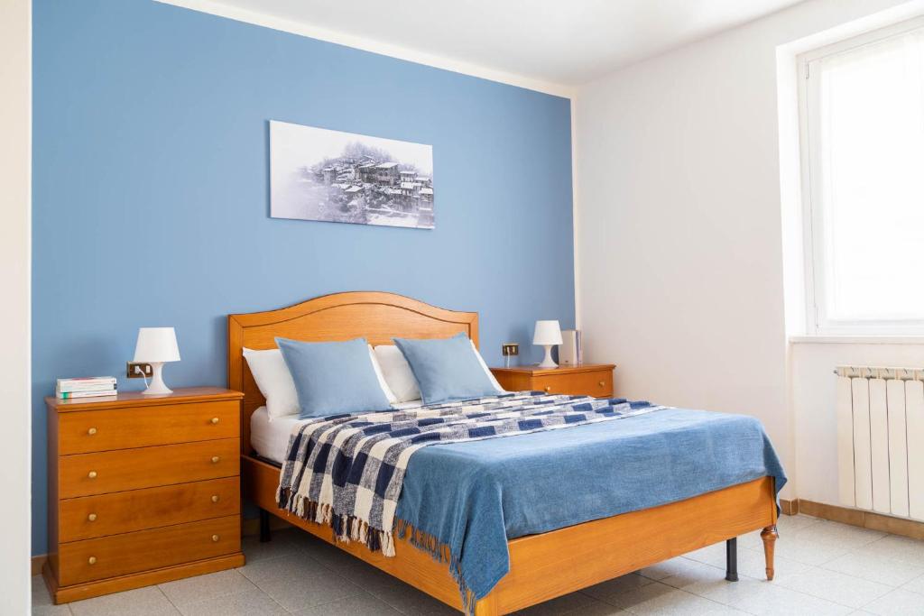 een slaapkamer met een bed met een blauwe muur bij CasaLina in Berbenno di Valtellina