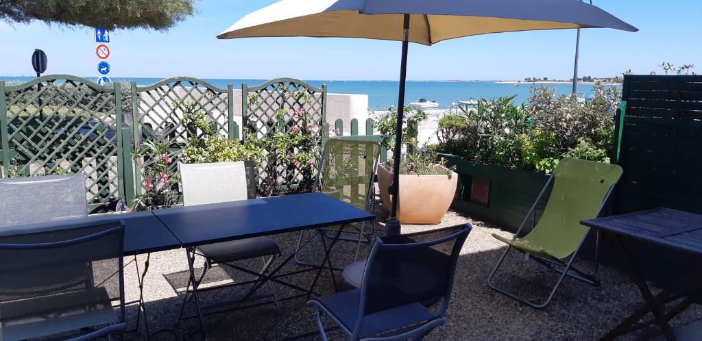 une table et des chaises bleues avec un parasol et l'océan dans l'établissement MAISON DE LA COTE, à La Flotte