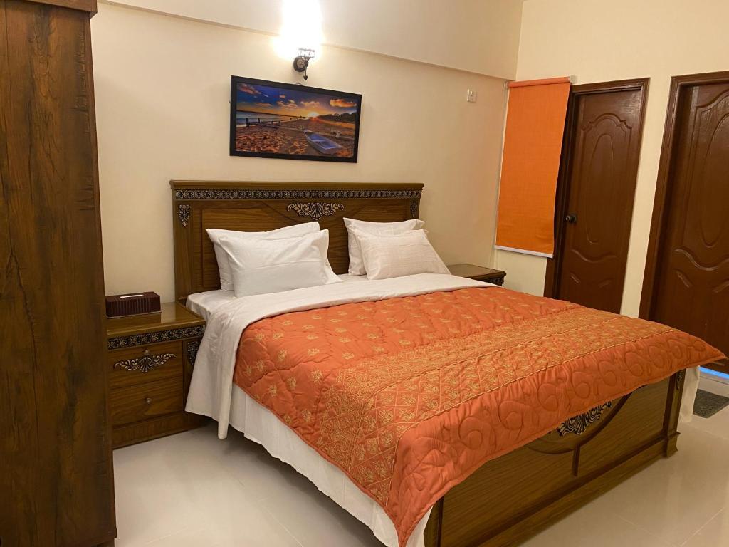 a bedroom with a bed with an orange comforter at 3 Bed Apartment in Karachi