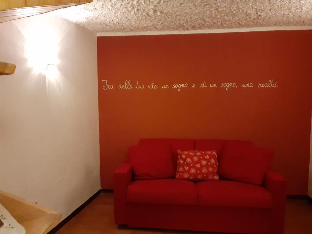 un sofá rojo en una habitación con escritura en la pared en La Petite Maisonnette, Alloggio ad uso turistico VDA INTROD n 0025 en Introd
