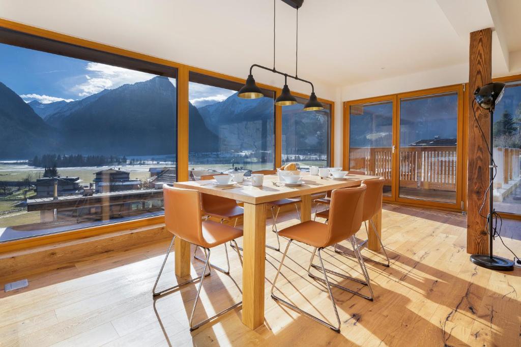a dining room with a table and chairs and a large window at Exklusives Chalet mit Gletscherblick in Neukirchen am Großvenediger