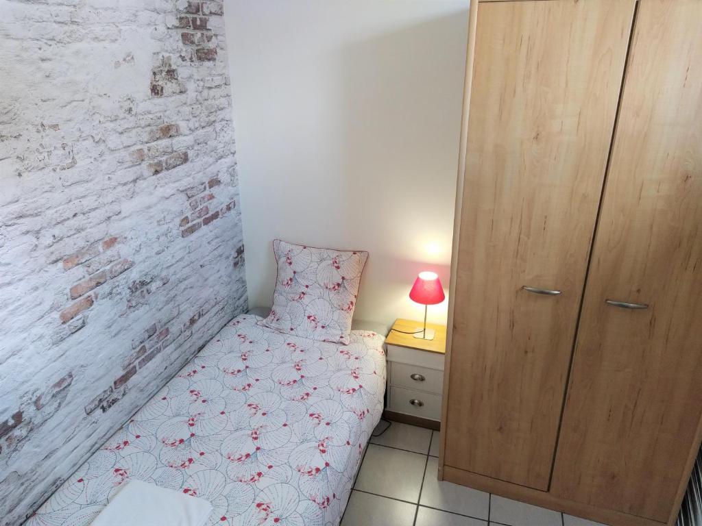 a small bedroom with a bed and a brick wall at Les Gîtes d&#39;Angres - gîte n°1 in Angres