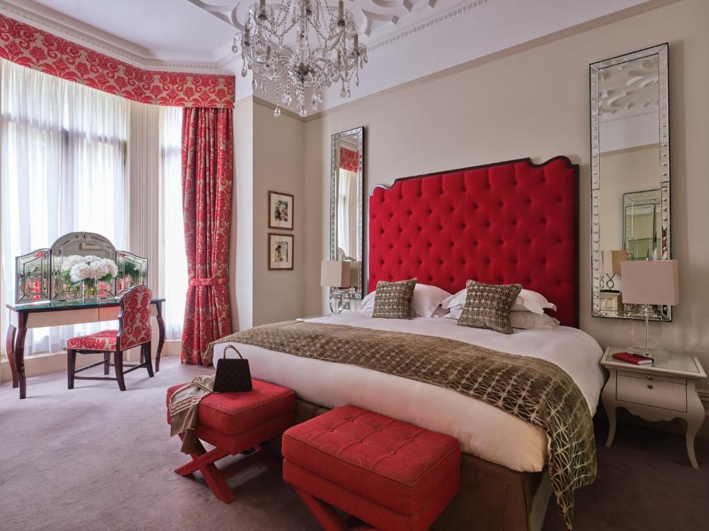 een slaapkamer met een groot bed en een rood hoofdeinde bij The Apartments by The Sloane Club in Londen