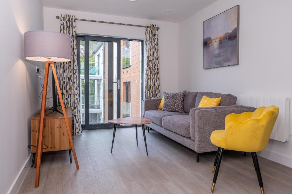 a living room with a couch and a yellow chair at 4 Rockham - Luxury Apartment at Byron Woolacombe, only 4 minute walk to Woolacombe Beach! in Woolacombe