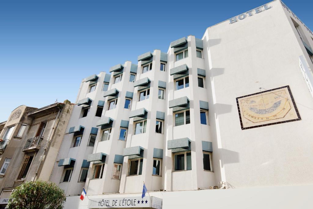 un bâtiment blanc avec un panneau sur son côté dans l'établissement Hôtel de l'Étoile, à Antibes