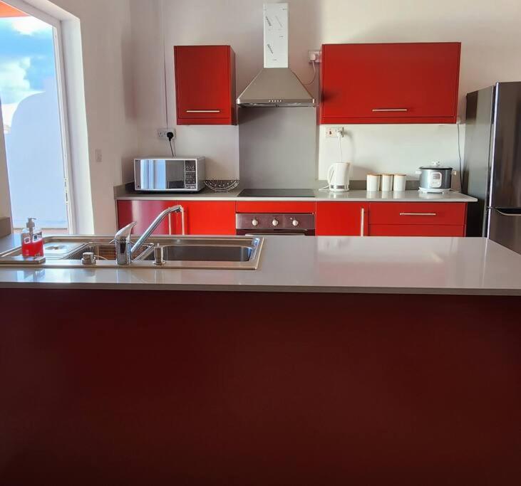 een keuken met rode kasten en roestvrijstalen apparatuur bij Peaceful holidays in Pereybere in Pereybere