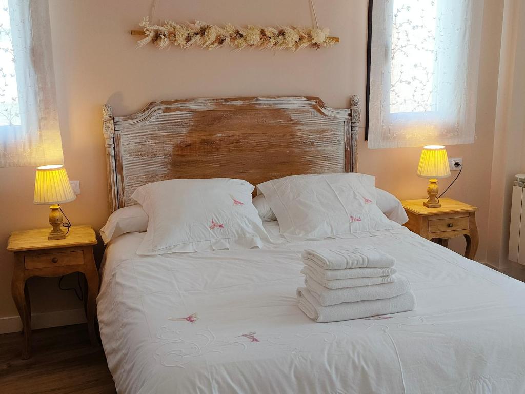 1 cama blanca con toallas y 2 lámparas en Apartamentos Antonia en Cuzcurrita-Río Tirón