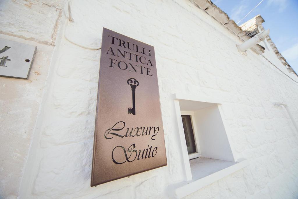 un cartello sul lato di un edificio bianco di Trulli Antica Fonte Luxury Suite ad Alberobello