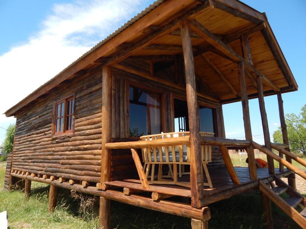 Cabaña de madera con porche en un campo en Complejo Las Lechuzas Cabaña 1 en San Miguel del Monte