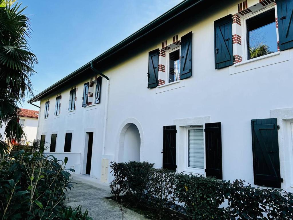 a white house with black windows and a palm tree at Appartement Cambo-les-Bains, 3 pièces, 4 personnes - FR-1-495-115 in Cambo-les-Bains