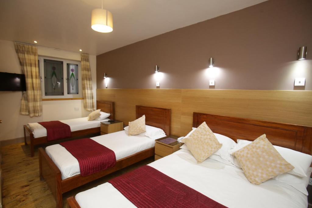 um quarto de hotel com três camas num quarto em The Merchant City Inn em Glasgow