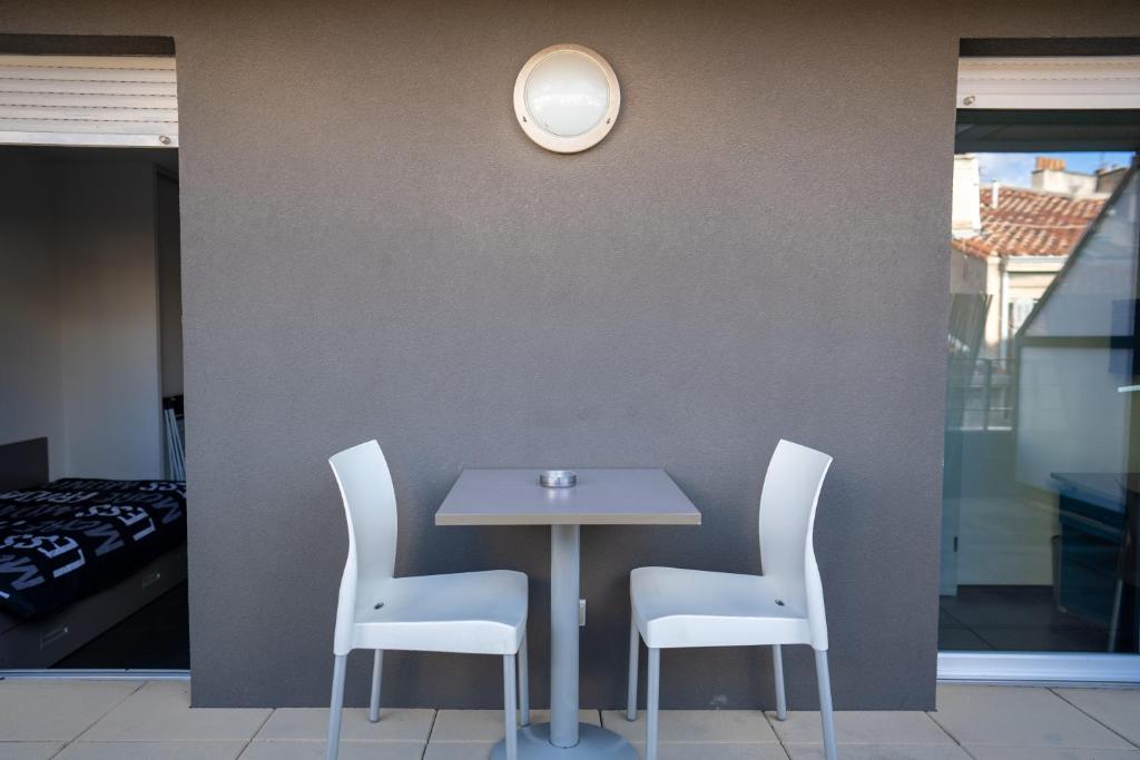 a table with white chairs and a clock on a wall at Le Stratège in Marseille