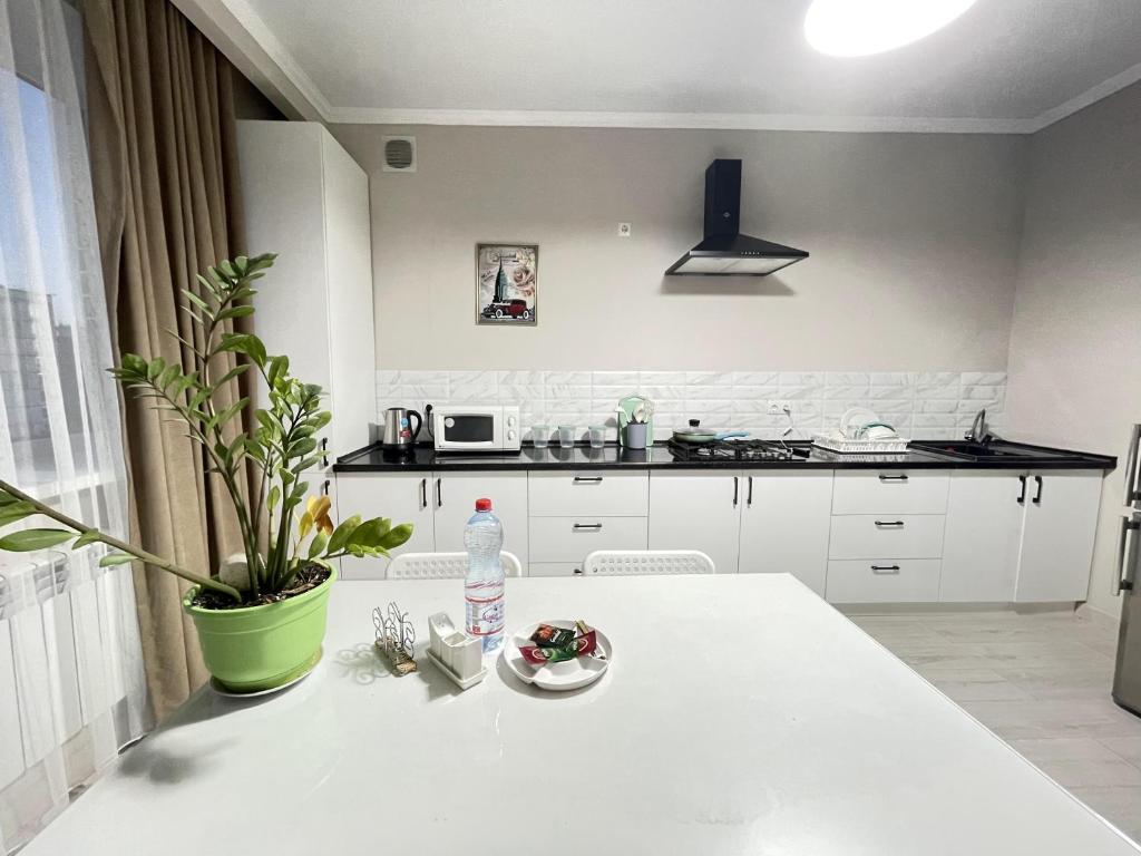 a white kitchen with a white table with a bottle of water at # 50 Солнечная комфортная студия in Atyraū