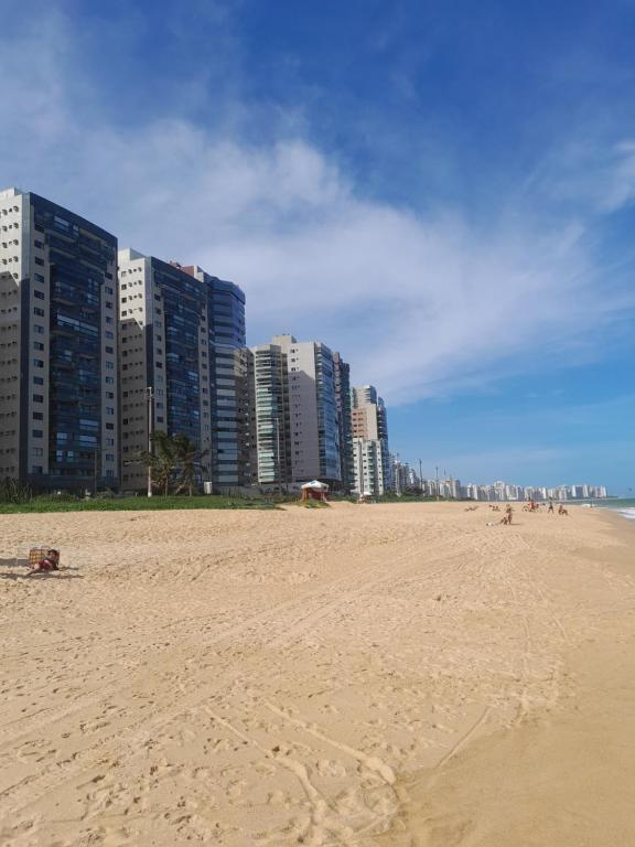 een zandstrand met hoge gebouwen op de achtergrond bij Apartamento perto da praia de Itaparica in Vila Velha
