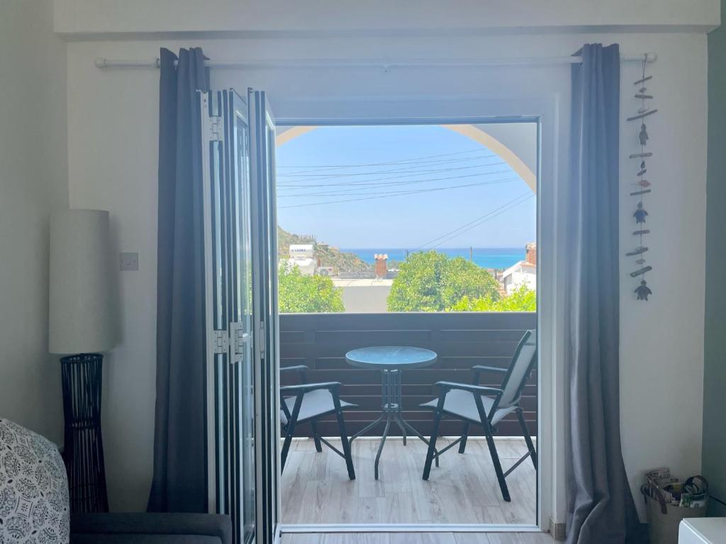 a room with a balcony with a table and chairs at Horizon Pissouri Bay 1 bedroom apartment with communal pool in Pissouri