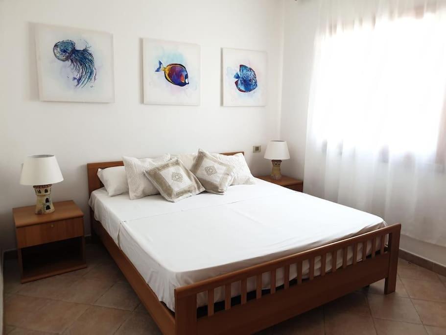 sypialnia z łóżkiem z trzema zdjęciami na ścianie w obiekcie comfortable appartment close to the beach w mieście Isola Rossa