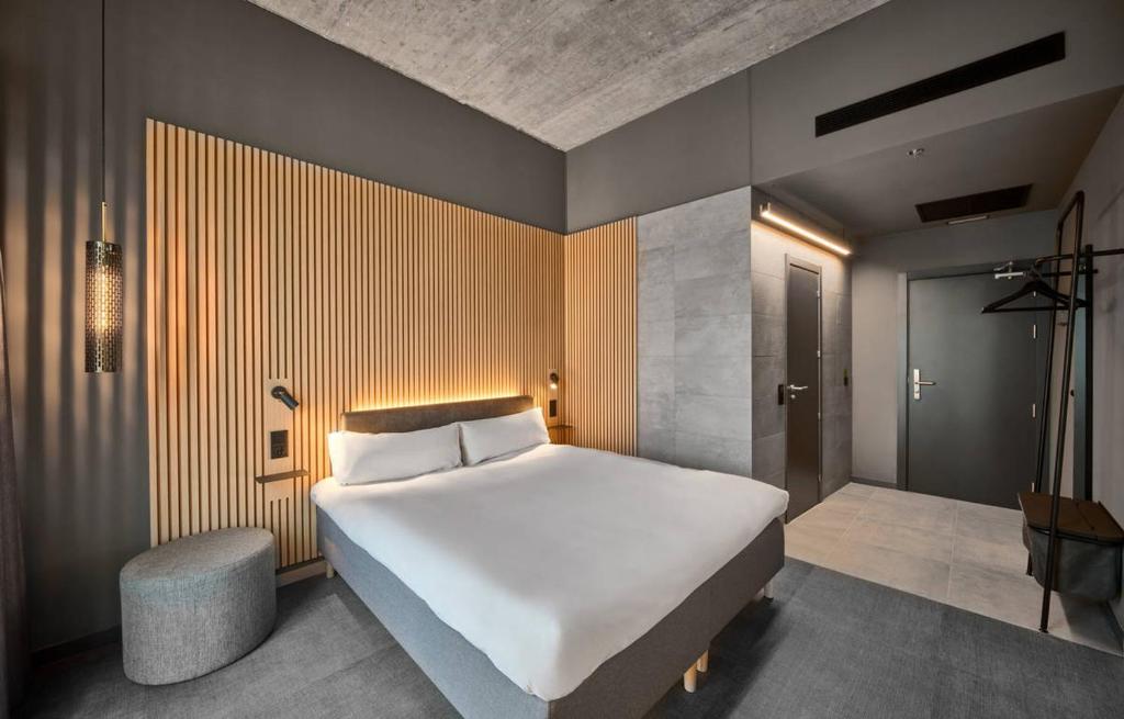 a bedroom with a large white bed and a stool at Zleep Madrid Airport in Madrid