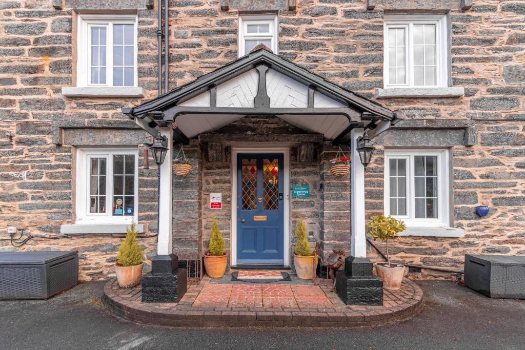 a blue door on a brick building with potted plants at Glyntwrog House in Betws-y-coed