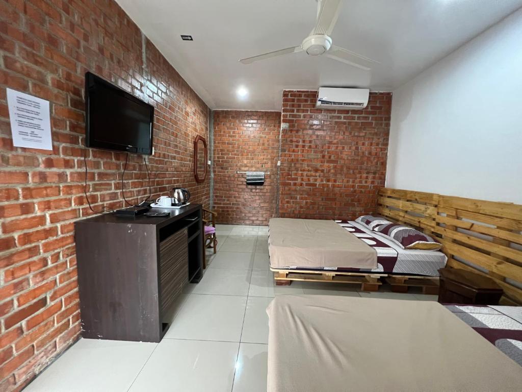 a room with two beds and a brick wall at Ujud Sepakat Homestay in Malacca
