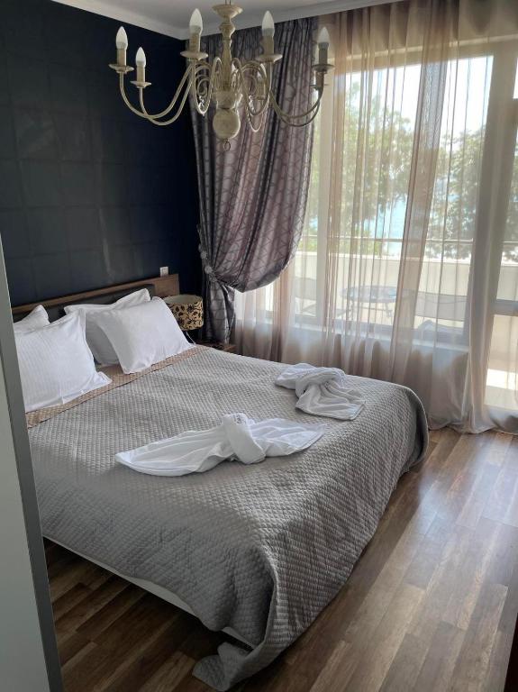 Un dormitorio con una cama con sábanas blancas y una lámpara de araña. en Deluxe Apartments Приморско en Primorsko