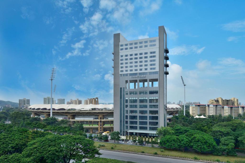 a tall white building in front of a city at Courtyard by Marriott Navi Mumbai in Navi Mumbai