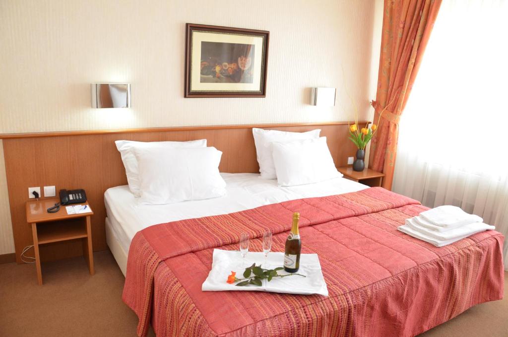 a hotel room with a bed with a bottle of champagne at Hotel Bellevue in Skopje