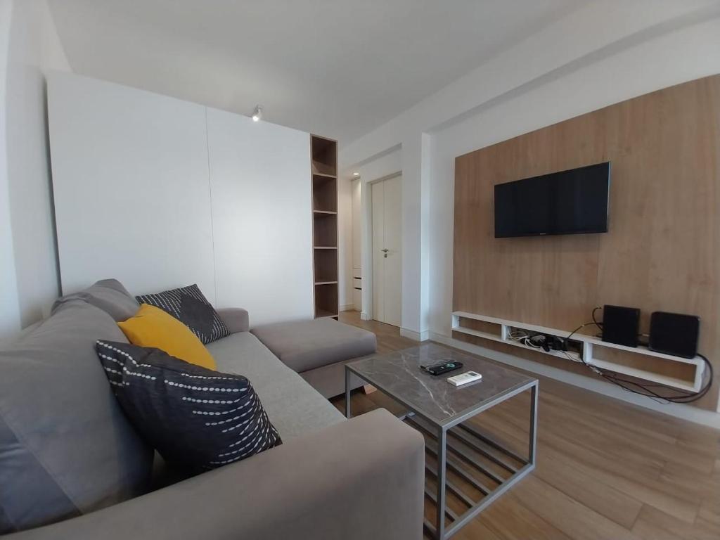 uma sala de estar com um sofá e uma televisão na parede em Apart Cid Campeador em Buenos Aires