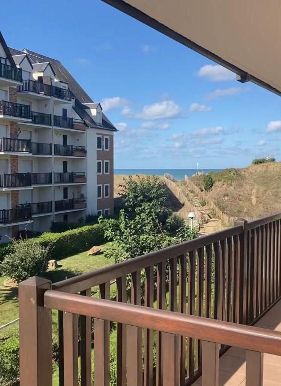 Elle comprend un balcon offrant une vue sur un bâtiment et l'océan. dans l'établissement Charmant Studio Front de Mer, à Cabourg