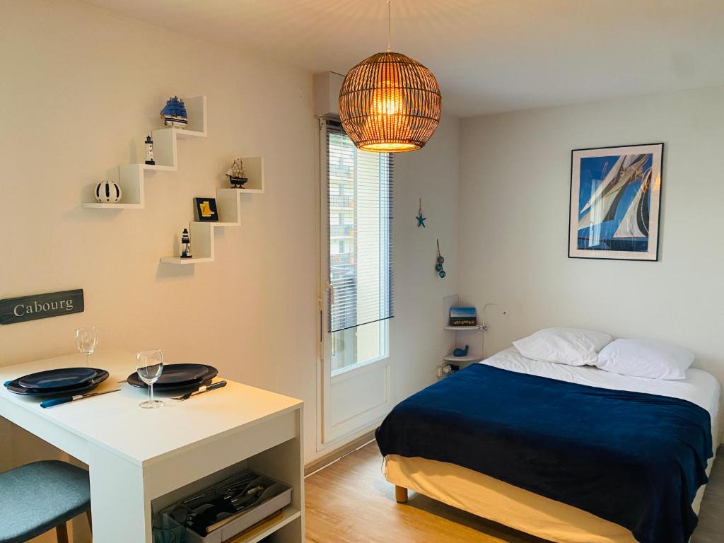 - une chambre avec un lit, une table et un bureau dans l'établissement Charmant Studio Front de Mer, à Cabourg