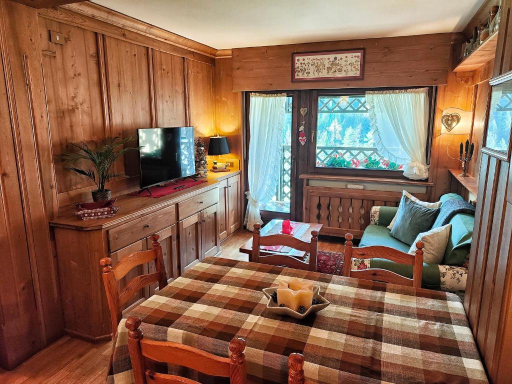 ein Wohnzimmer mit einem Tisch, einem TV und einem Sofa in der Unterkunft Hometoday - Appartamento nel cuore di San Vito di Cadore in San Vito di Cadore