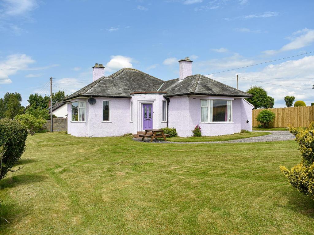 ein weißes Haus mit einer lila Tür auf einem Hof in der Unterkunft Delmonte in Langwathby