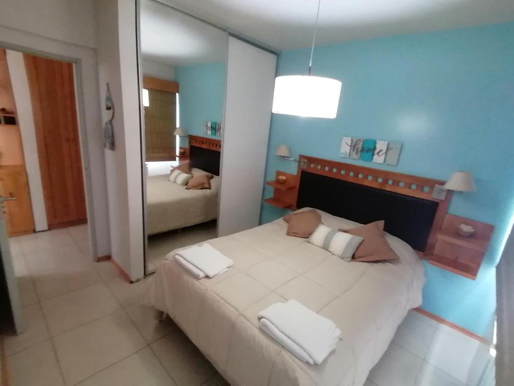 1 dormitorio con 1 cama blanca grande y espejo en Dpto Roca en San Martín de los Andes