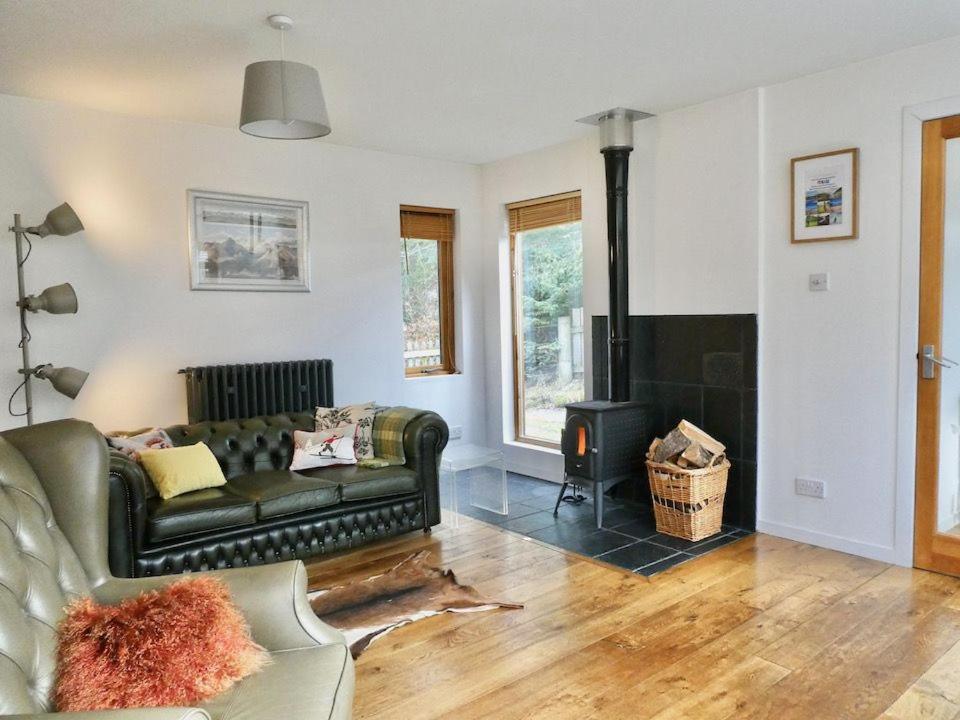 a living room with a couch and a fireplace at Baltinna East - by Where Stags Roar in Newtonmore