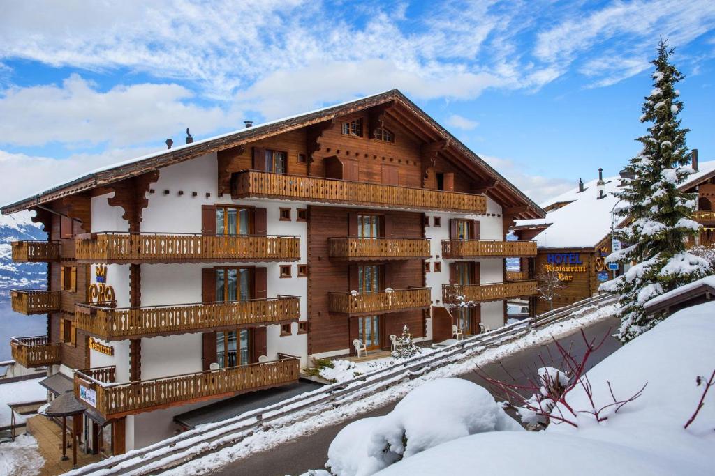 um grande edifício com varandas de madeira na neve em Hôtel Chalet Royal em Veysonnaz