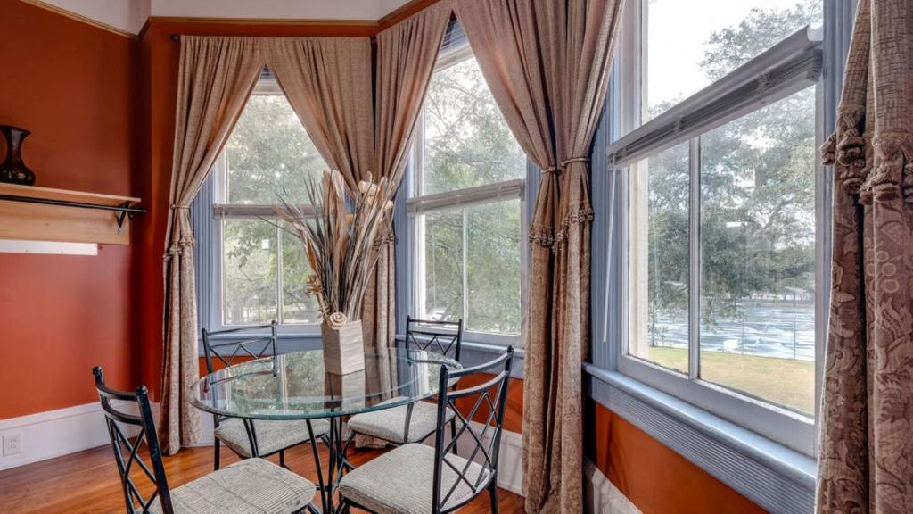 a dining room with a glass table in front of windows at Forsyth Park 2 Bedroom Beauty in Savannah