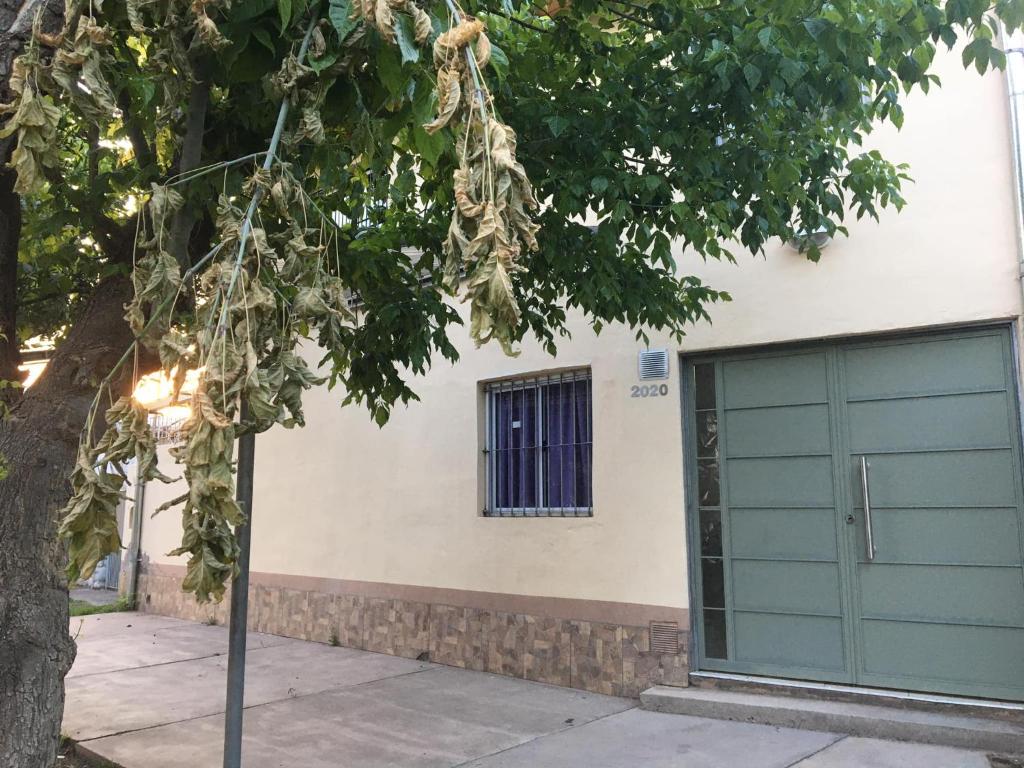 un edificio con una puerta de garaje verde y un árbol en Departamento en San Rafael en San Rafael