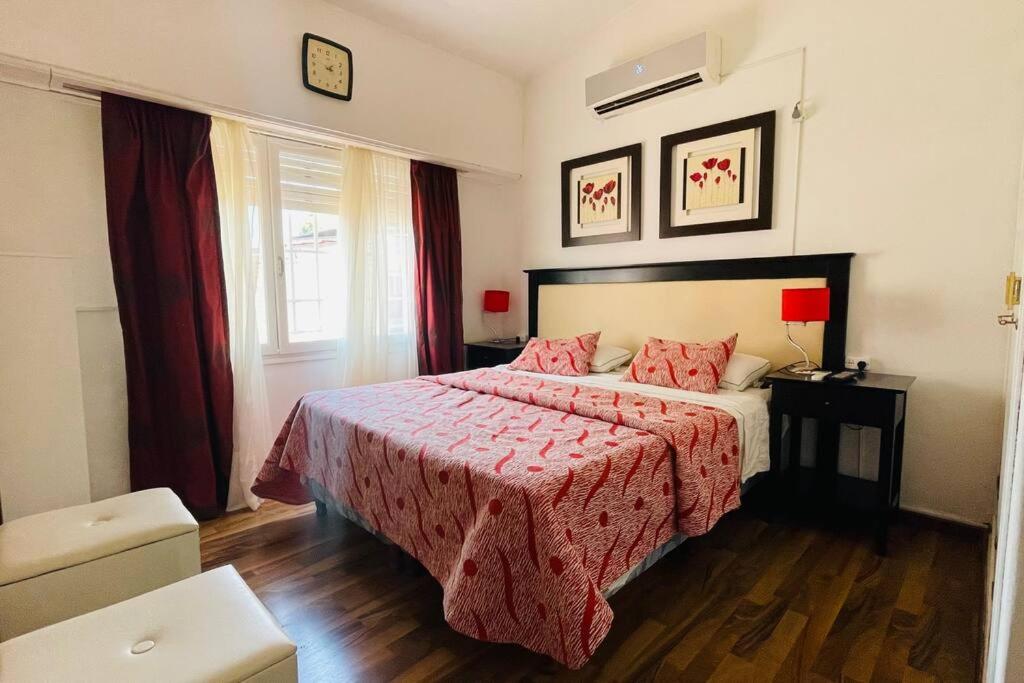 um quarto com uma cama com um cobertor vermelho e uma janela em Excelente Casa c/ Pileta Cerca del Centro em Villa Carlos Paz