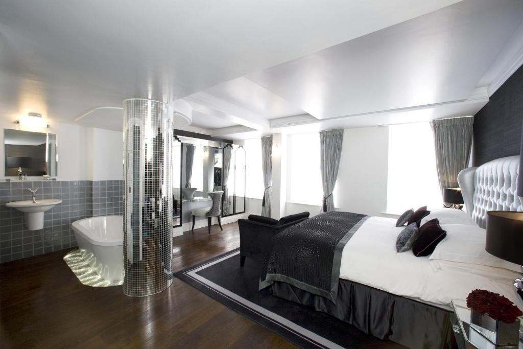 a hotel room with a large bed and a large window at Karma Sanctum Soho Hotel in London