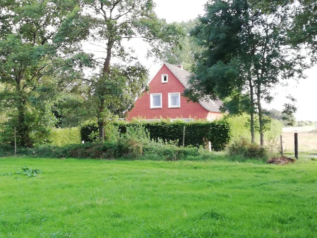 una casa roja en un campo de césped verde en Ediths Haus, en Rhauderfehn