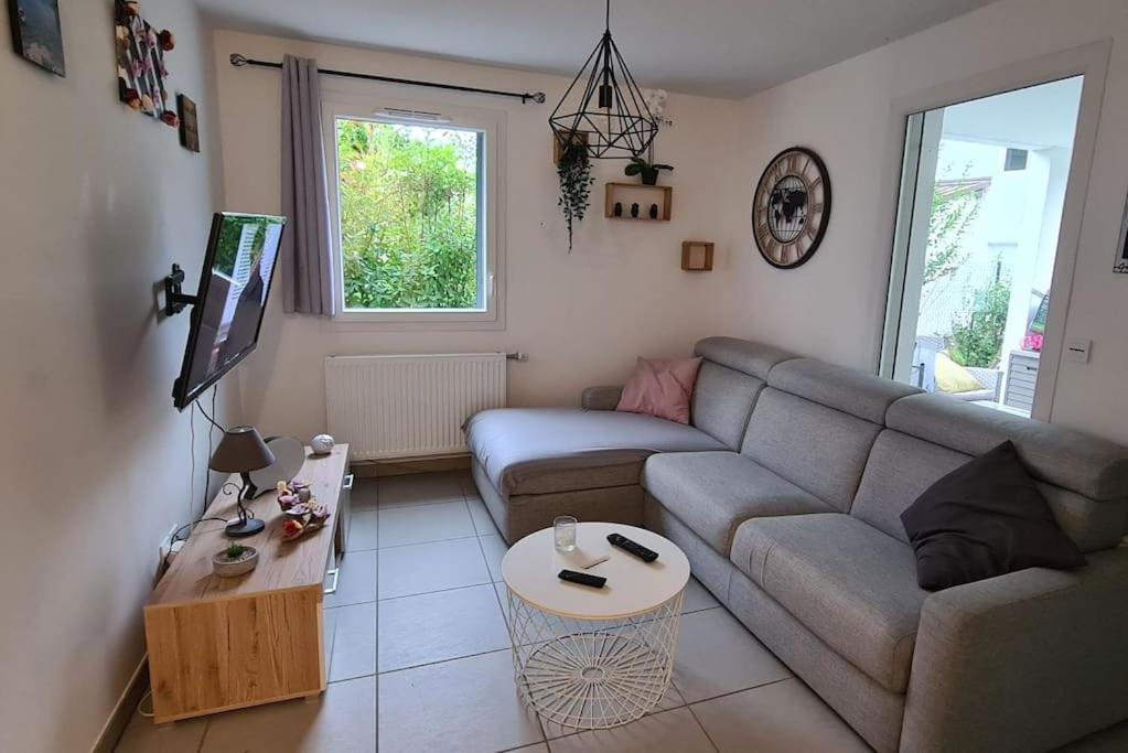 ein Wohnzimmer mit einem Sofa und einem Tisch in der Unterkunft Joli Appartement vue montagne, cosy avec jardin in Bonneville