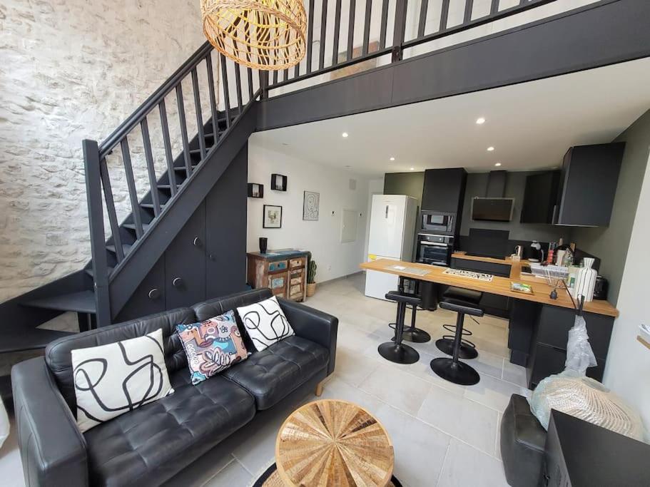 Il comprend un salon avec un canapé en cuir noir et une cuisine. dans l'établissement Maison contemporaine 47m² proche plage, commerces, à Saint-Georges-de-Didonne