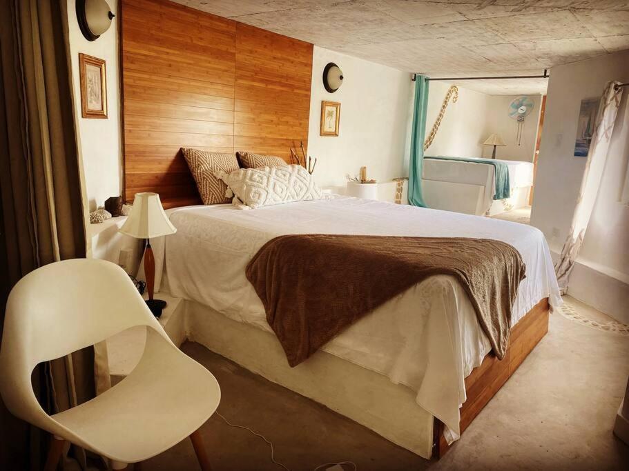1 dormitorio con 1 cama grande y 1 silla blanca en Forever Beach Apartment, en Sheerness