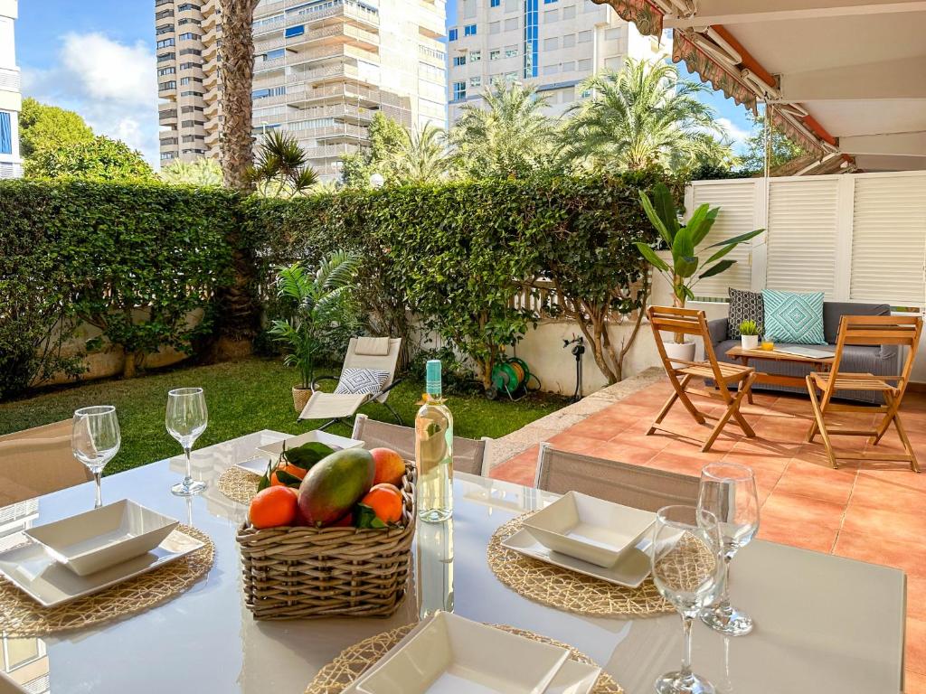 a table with a basket of fruit and a bottle of wine at Jardín Playa San Juan in Alicante