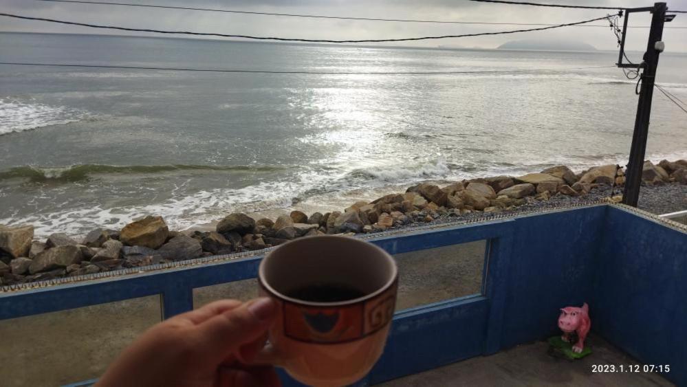 eine Person mit einer Tasse Kaffee und Meerblick in der Unterkunft Pé na areia apt superior in Itapoa