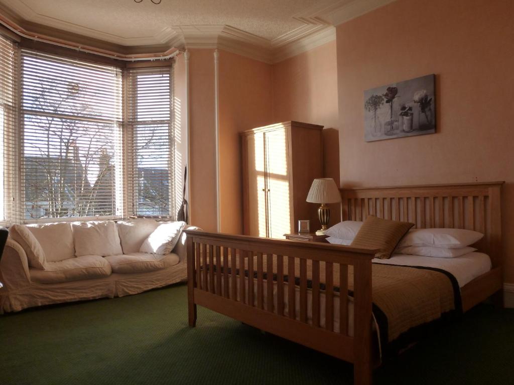 a bedroom with a bed and a couch in front of a window at Inn At The Park Hotel in Aberdeen