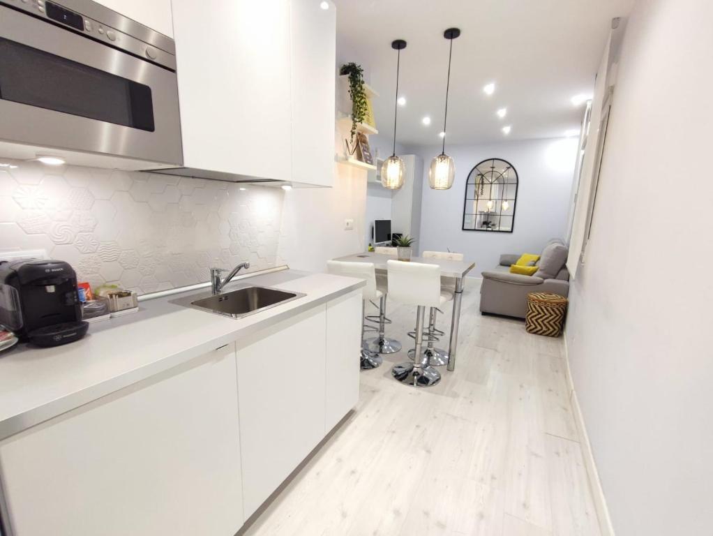 a kitchen with white cabinets and a sink and a living room at Apartamento con encanto in Madrid