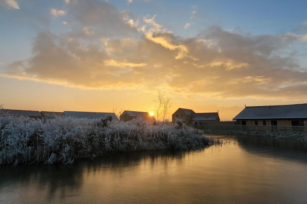 um pôr do sol sobre um rio com neve nas margens em Rowan House, Ashlin Farm Barns em Lincoln