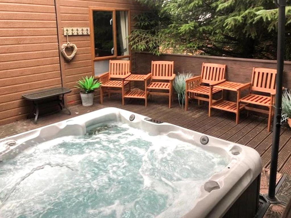 a hot tub on a deck with chairs and a table at Griffon Lodge - Uk3469 in Felton