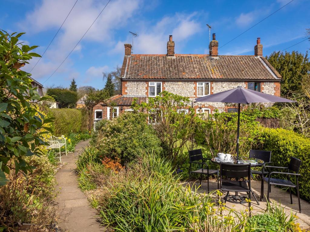 a house with a table and chairs and an umbrella at Primrose Cottage in Aylmerton